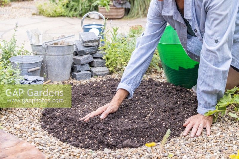 Woman spreading compost evenly around the marked area