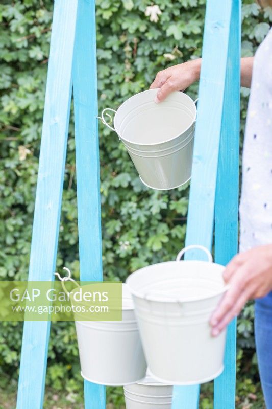 Woman hanging buckets on the hooks on alternate sides