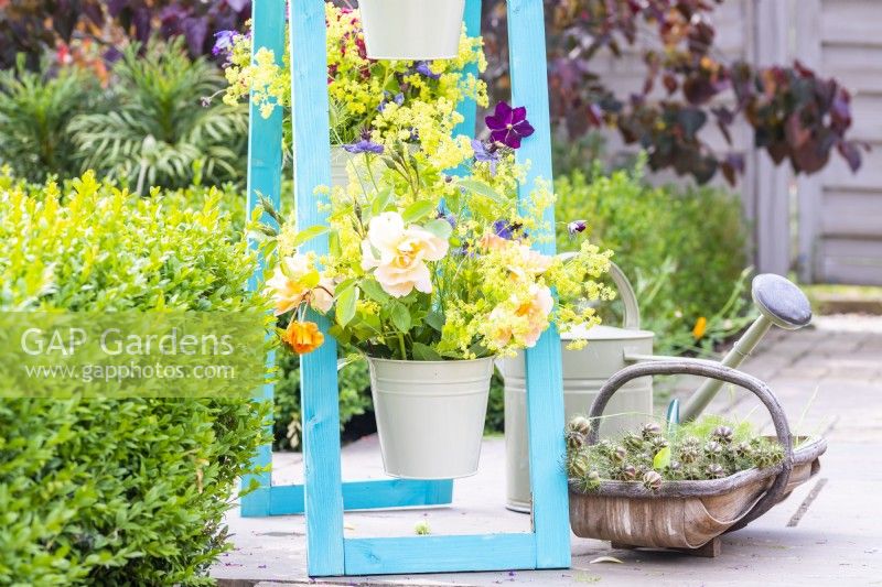 Cut flowers in buckets on painted wooden A frame