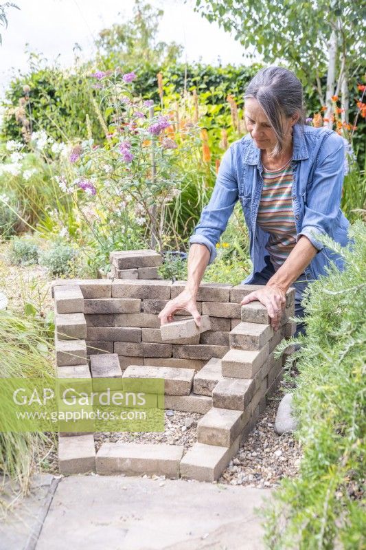Woman creating a sloped wedge with the pavers