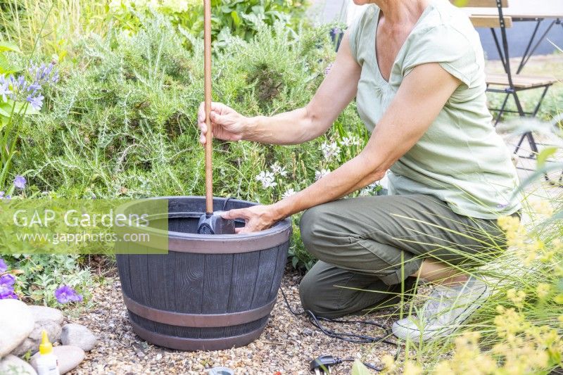 Woman placing pump with copper pipe into the barrel