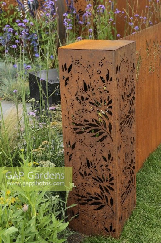 Detail of a rectangular filigree corten steel structure - Sunburst Garden, RHS Hampton Court Palace Garden Festival 2022.  Designers:  Charlie Bloom and Simon Webster  