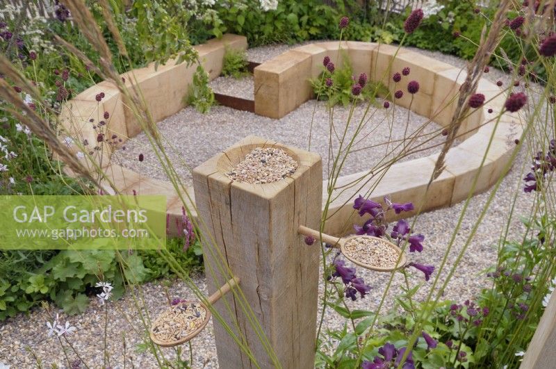 A quirky bird feeder filled with seeds on the edge of The Wooden Spoon Garden, RHS Hampton Court Palace Garden Festival 2022.  Designers:  Toni Bowater and Lucy Welsh
