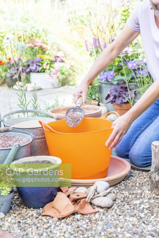 Woman filling the trug with four parts sand, two parts gravel and one part soil