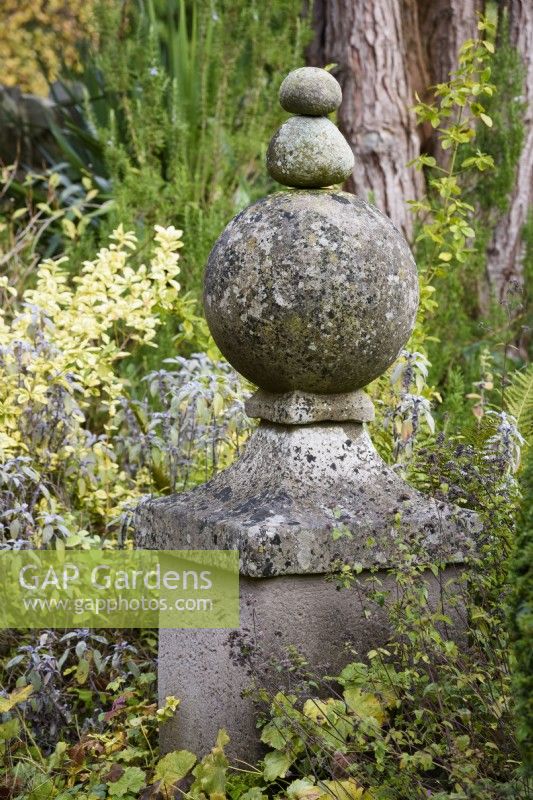 Stone gate finial topped with pebbles in a country garden in November