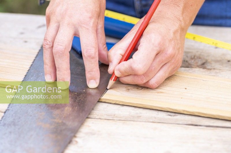 Woman marking where to cut the wooden plank