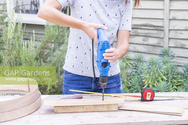Woman drilling three holes in the longest piece of wood