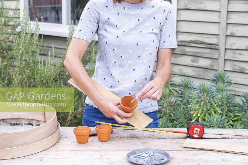 Woman fixing the pots to the wooden plank using washers, wingnuts and bolts