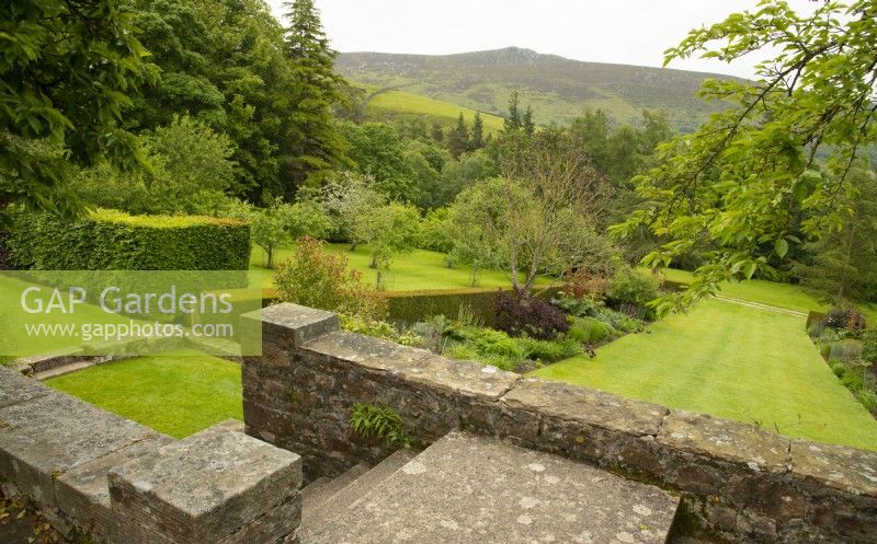A view over the red borders to Simon's Seat from a terrace at Parcevall Hall Gardens in June.