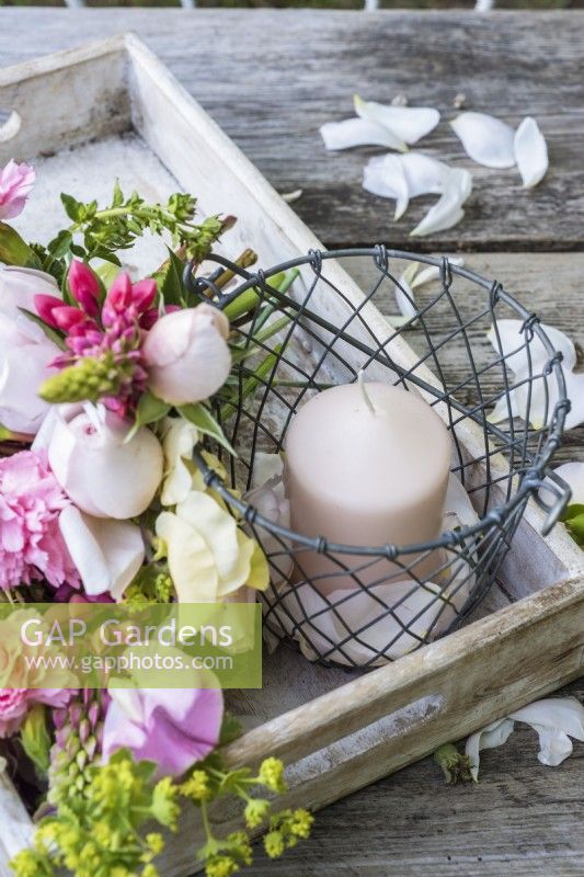 Candle with bouquet of pink and cream - Lathyrus odorata, Dianthus, Lupins, Alchemilla mollis and roses in wooden tray