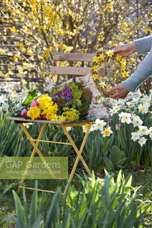 Woman placing wreath made of willow twigs and daffodils on chair.