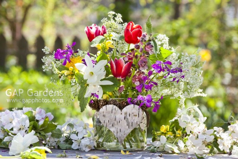 Flower bouquet containing tulips, daffodil and wild flowers from the garden in decorative glass jar.