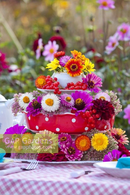 Floral arrangement on laid table containing strawflowers, zinnia, dahlia and rowan berries.