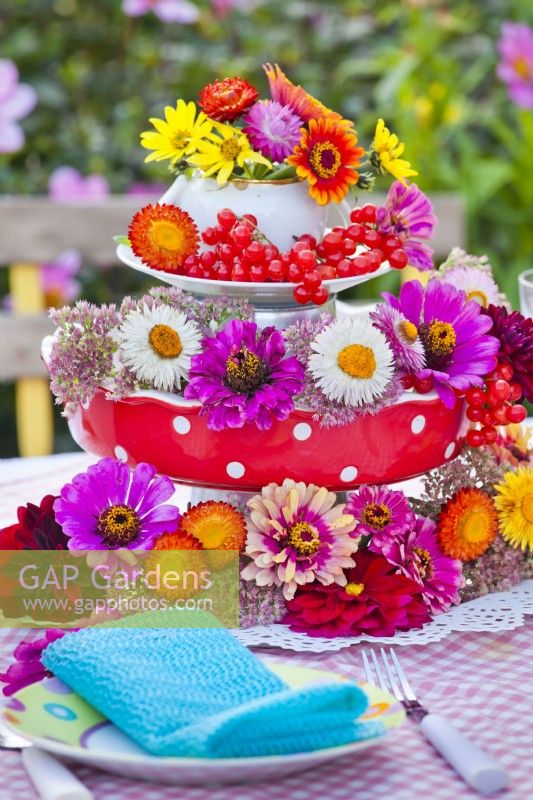 Floral arrangement on laid table containing strawflowers, zinnia, dahlia and rowan berries.