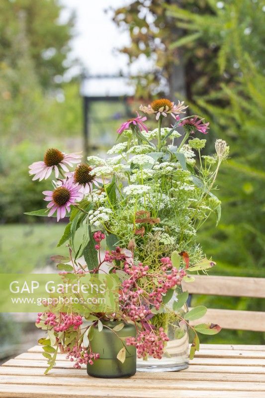 Arrangement containing Echinacea 'Sunseekers Salmon', Ammi visnaga, and Sorbus berries on a wooden table
