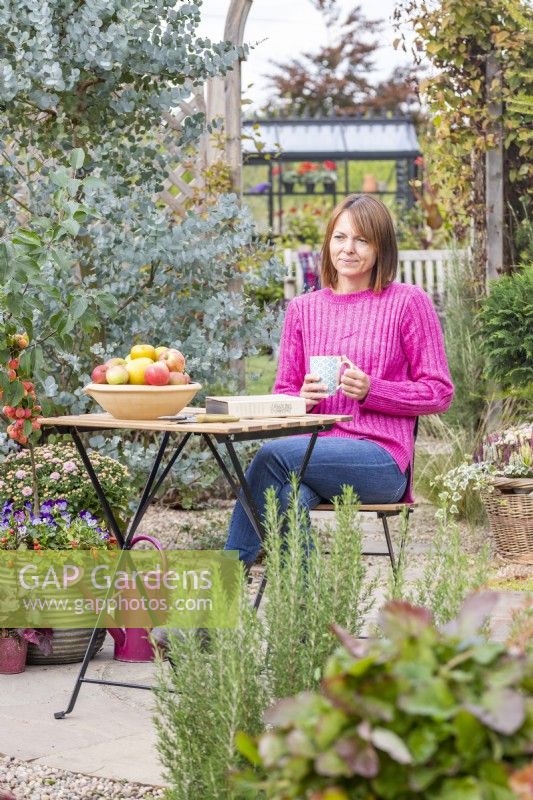 Woman sitting at table in a garden with a cup of tea