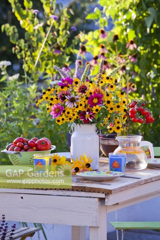 Flower bouquet in a milk can on the table containing Rudbeckia, Zinnia, Dahlia and Agastache.