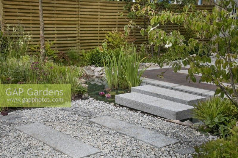 Path with long stepping stones towards raised meditation platform in The Memories of Mountains Garden Retreat Garden at BBC Gardeners World Live 2022