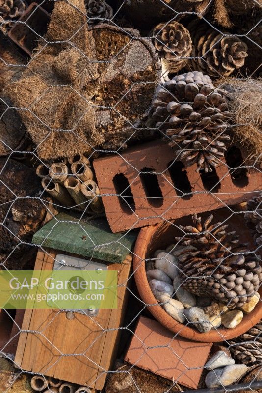 Looking at a section of a bug hotel, with old bricks, fir cones, bird box, bamboo canes and coconut matting encased with wire netting.