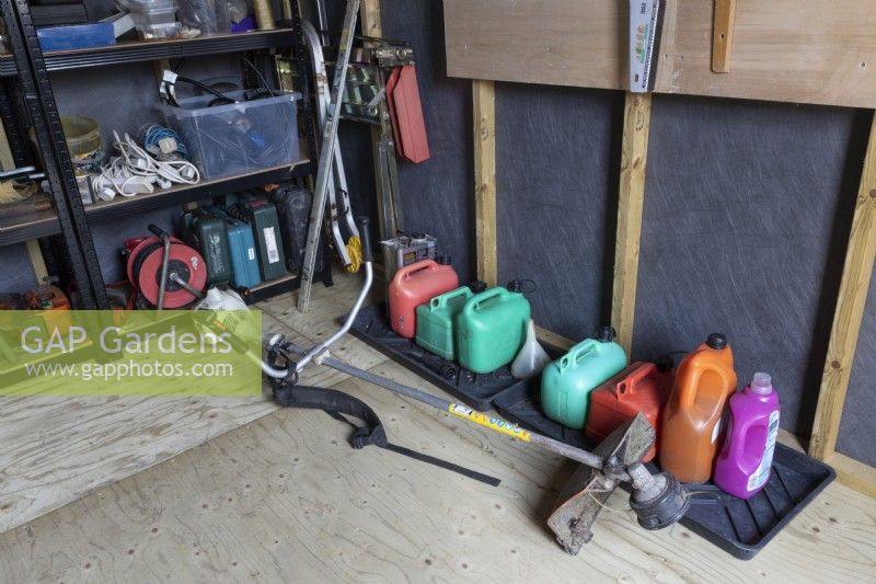 A professional Stihl strimmer lies on the floor in front of a row of fuel containers. Autumn.