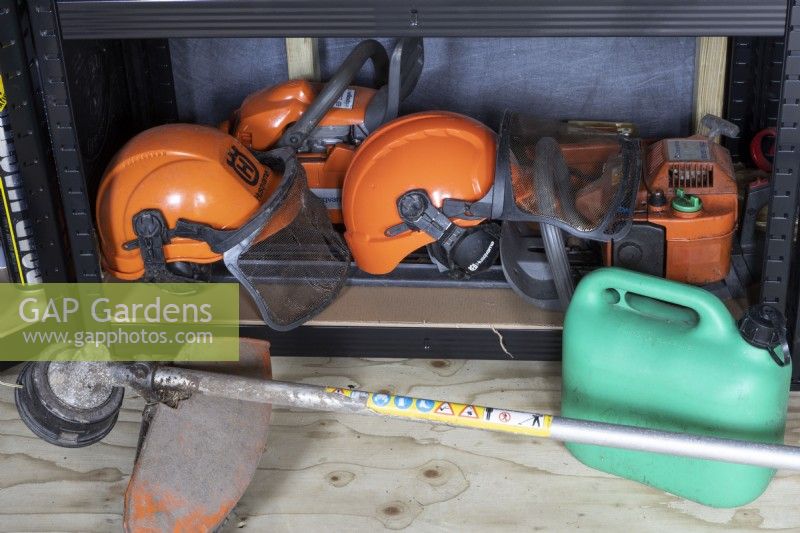 A professional Stihl strimmer lies on the floor in front of safety equipment and other paraphernalia including hard hats and visors. Autumn.