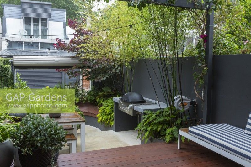 Inner city courtyard garden with a deck, bench seats raised garden beds and barbecue.