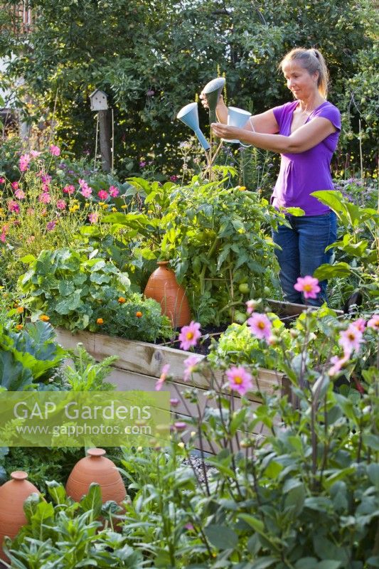 Woman placing sprinkler tops from watering can on the top of cane support for decoration and eye protection.