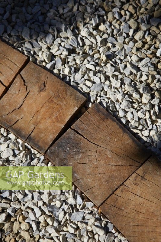 Slices of reclaimed Oak posts used as dividing detail on gravel pathway.