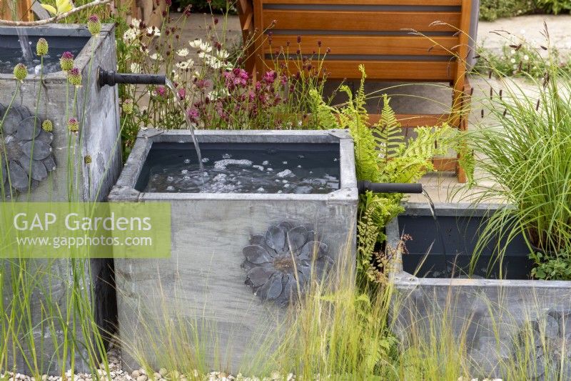 Three square lead-effect containers used as a cascading water feature with planting - Knolling with Daisies, RHS Hampton Court Palace Garden Festival 2022