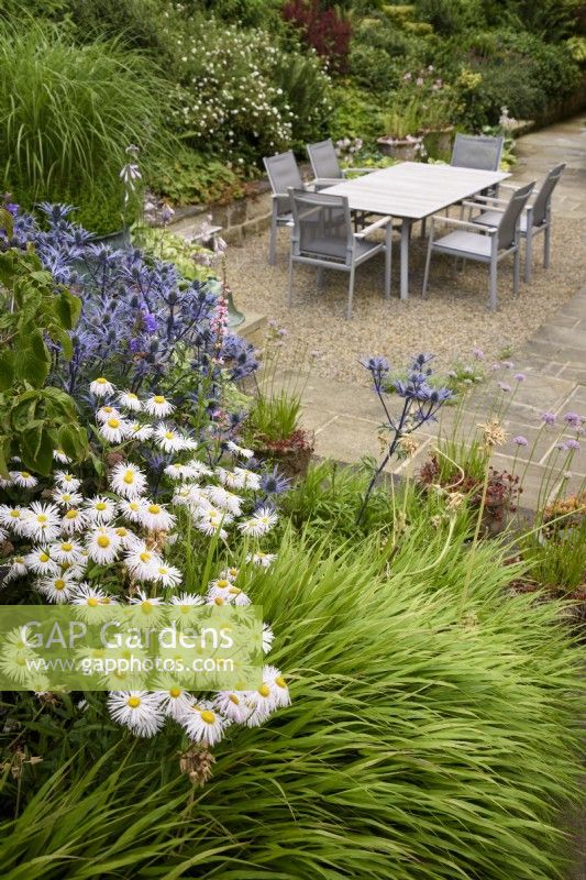 Courtyard garden with dining area surrounded by plants in the garden at Cow Close Cottage, North Yorkshire in July