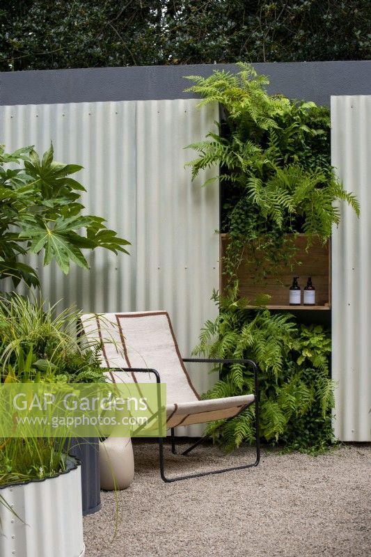 Chair next to a living wall with corrugated iron and wooden shelving - The Hot Tin Roof Garden, RHS Chelsea Flower Show 2021