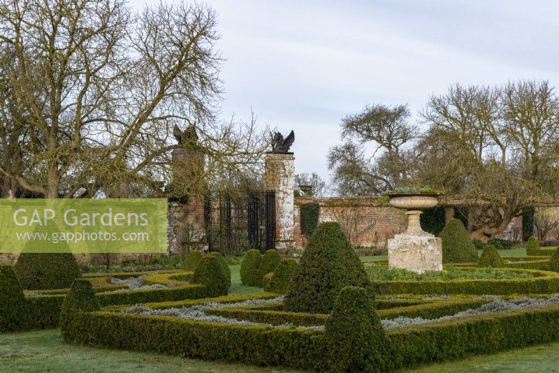 The parterre at Helmingham Hall is outlined with Buxus sempervirens, Box that is interplanted with Santolina incana. The stone urn in the circular bed is seasonally planted with wallflowers followed by cosmos.