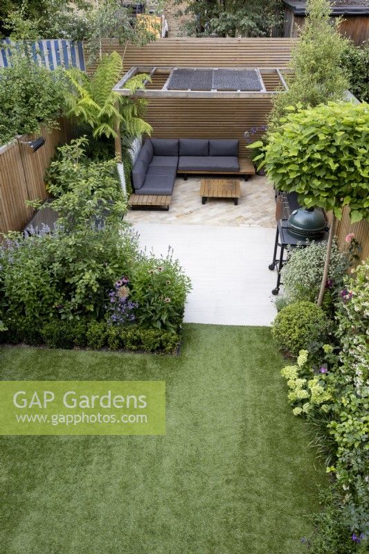 High view of small suburban garden with artificial lawn,  patio and wood pergola