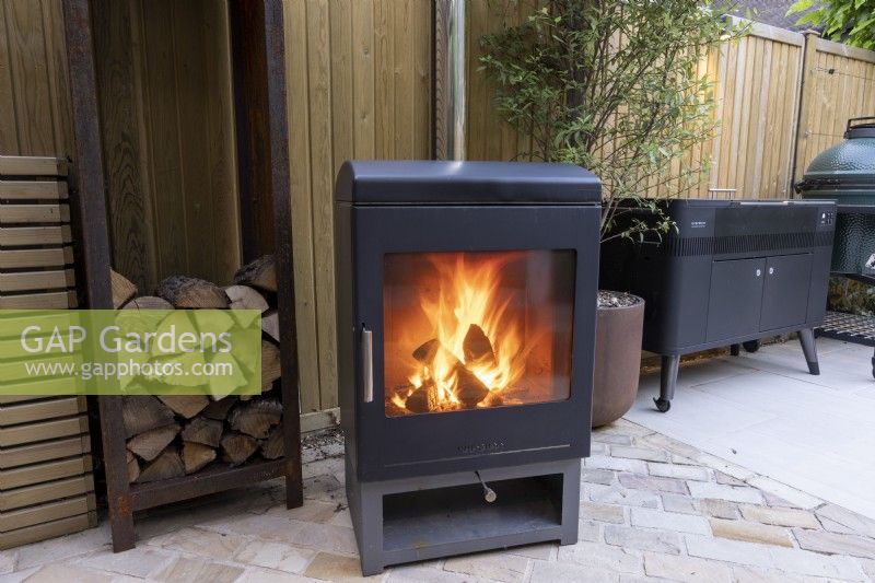 Log burner on contemporary patio area  with metal log store