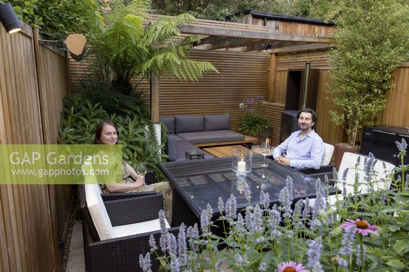 Man and woman sitting around table in small suburban garden