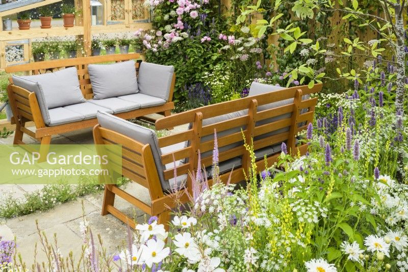 Seating area set surrounded by pastel planting including  white Cosmos Ammi majus, Agastache rugosa 'Liquorice Blue' - Knolling with Daisies, RHS Hampton Court Palace Garden Festival 2022