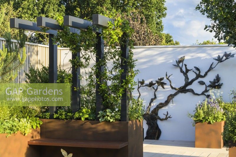 Pergola with climbing Trachelospermum jasminoidies and sculpture by Emma Rodgers  - John King Brain Tumor Foundation Garden, RHS Hampton Court Palace Garden Festival 2022