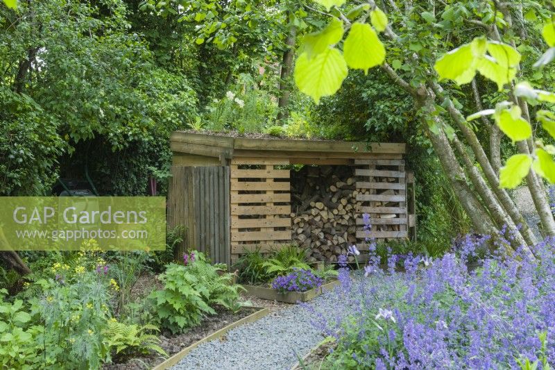 Log store incorporating recycled pallets and a green roof. June.