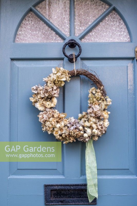 Dried Hydrangea wreath with green ribbon hanging from front door