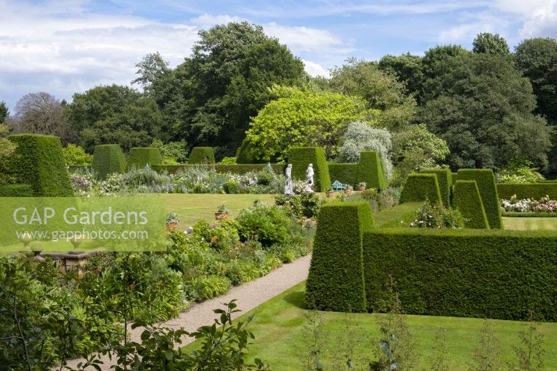 A view over the borders, topiary hedge, lawn and sculptures in the Italianate formal garden at Renishaw Hall and Gardens.