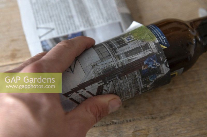 Making planting pots for seedlings from old newspapers. 
Two pages of a tabloid size newspaper first cut into three strips and with the leading edge folded is rolled over a 30cl beer bottle to create a tube. 