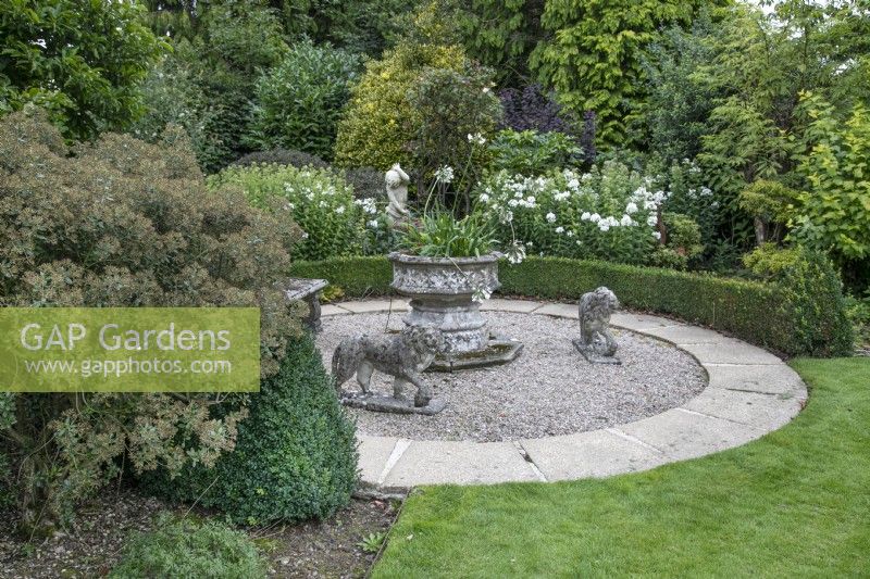 Circular seating area with stone lions at The Burrows Gardens, Derbyshire, in August