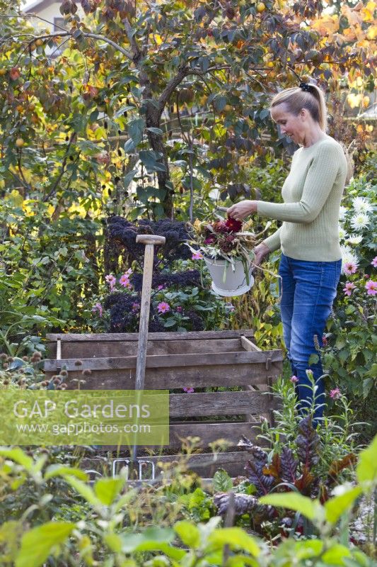 Woman adding waste from the kitchen garden to a compost bin.