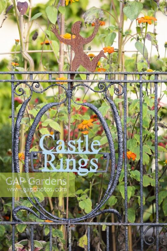 Gate with decorative name plate incorporated into the design in a country garden.