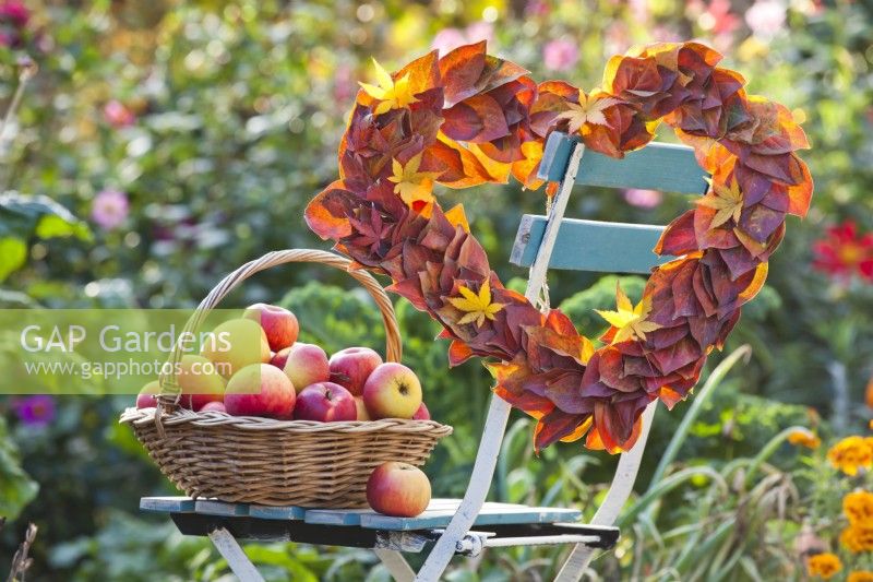 Heart shaped wreath made of maple  and persimmon leaves and harvested apples.