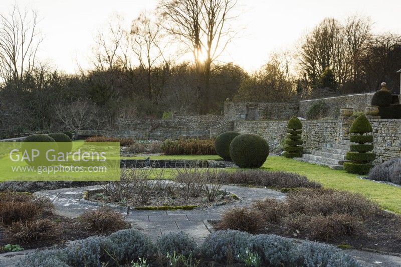 The Jewson Terrace at Cotswold Farm Gardens in February with geometric beds and clipped evergreens including yew and box.