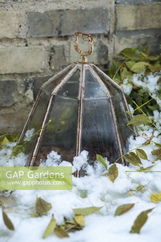 Cast iron and glass octagonal lantern cloche next to brick wall with snow. December.