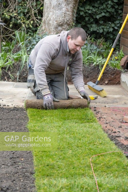 A worker laying new turf during the makeover of a London garden.