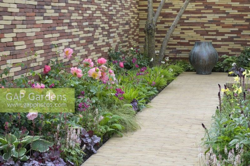 Border along  clay paver path with Paeonia 'Coral Sunset', Rose 'Queen of Sweden', Tiarella 'Pink Skyrocket' and Hakonechloa macra - The Stitcher's Garden, RHS Chelsea Flower Show 2022 - Silver Medal