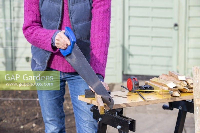 Woman sawing lengths of wood into wedges